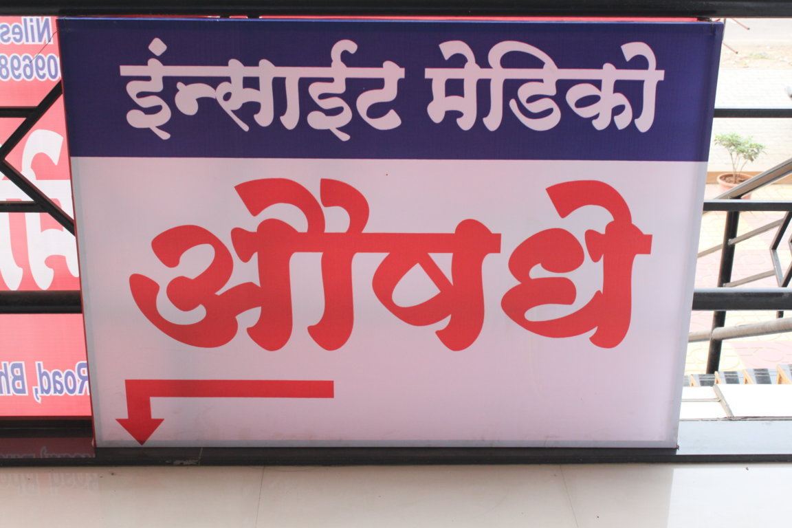 Bilingual Insight Medico pharmacy directional signboard mounted at the Insight Institute entrance, pointing patients toward the in-house chemist